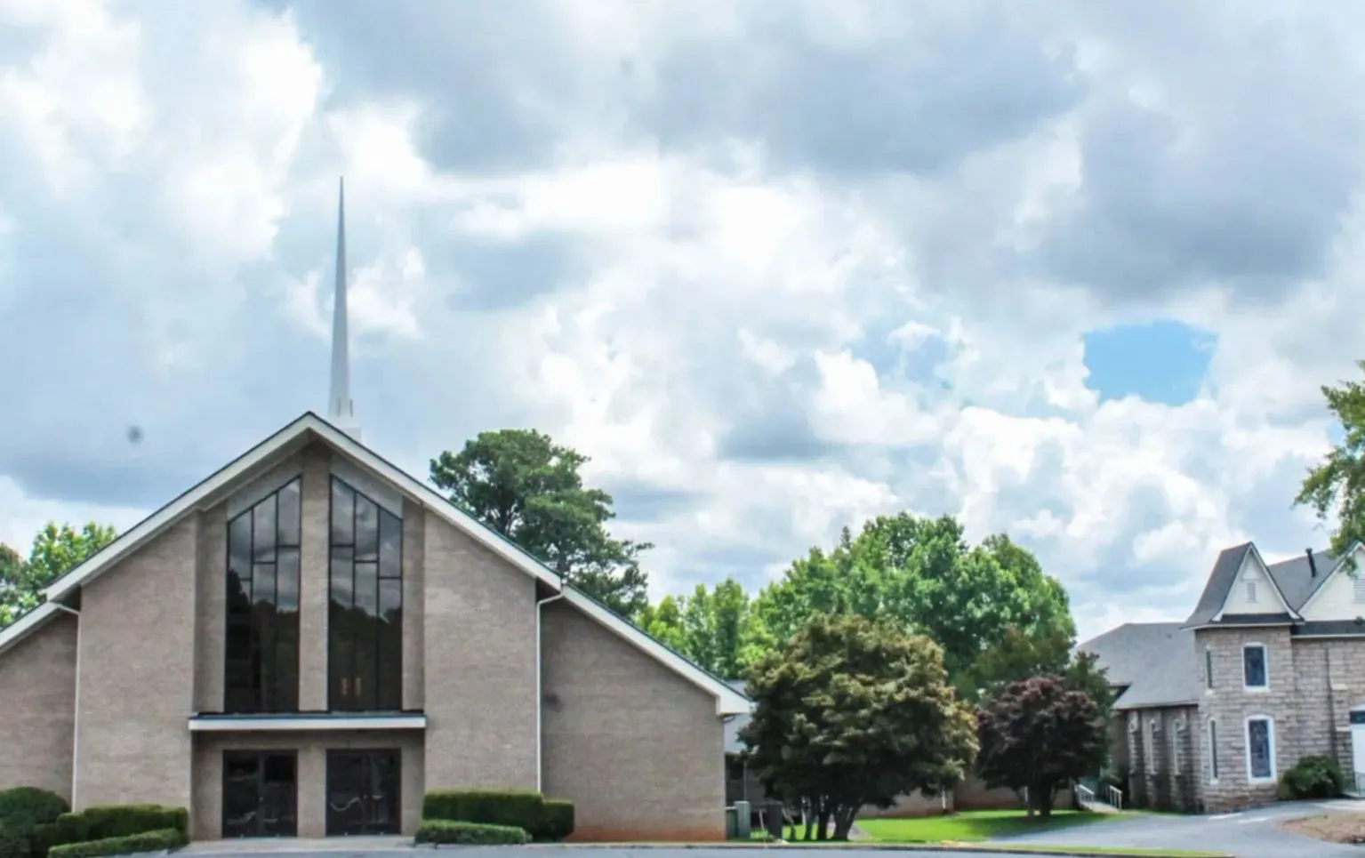 The Ramah Baptist Church sanctuary with its white steeple, beside the historic stone chapel