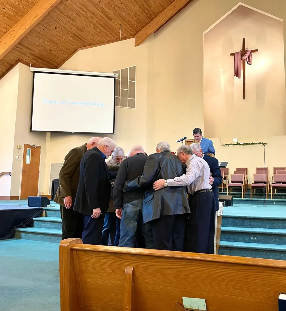 Men of the church gathered in prayer at the front of the sanctuary