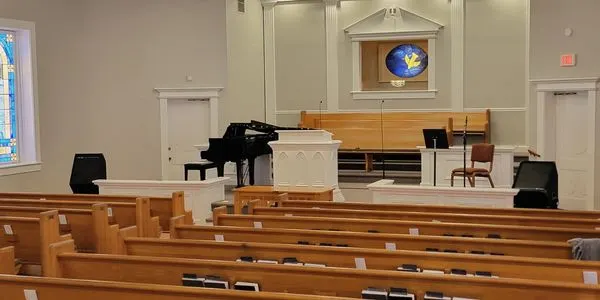 A sanctuary at Ramah with wooden pews and a grand piano