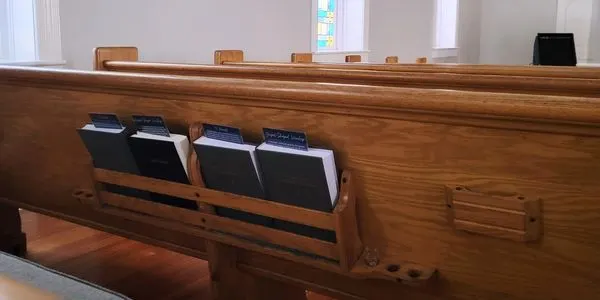 Hymnals in a wooden pew rack