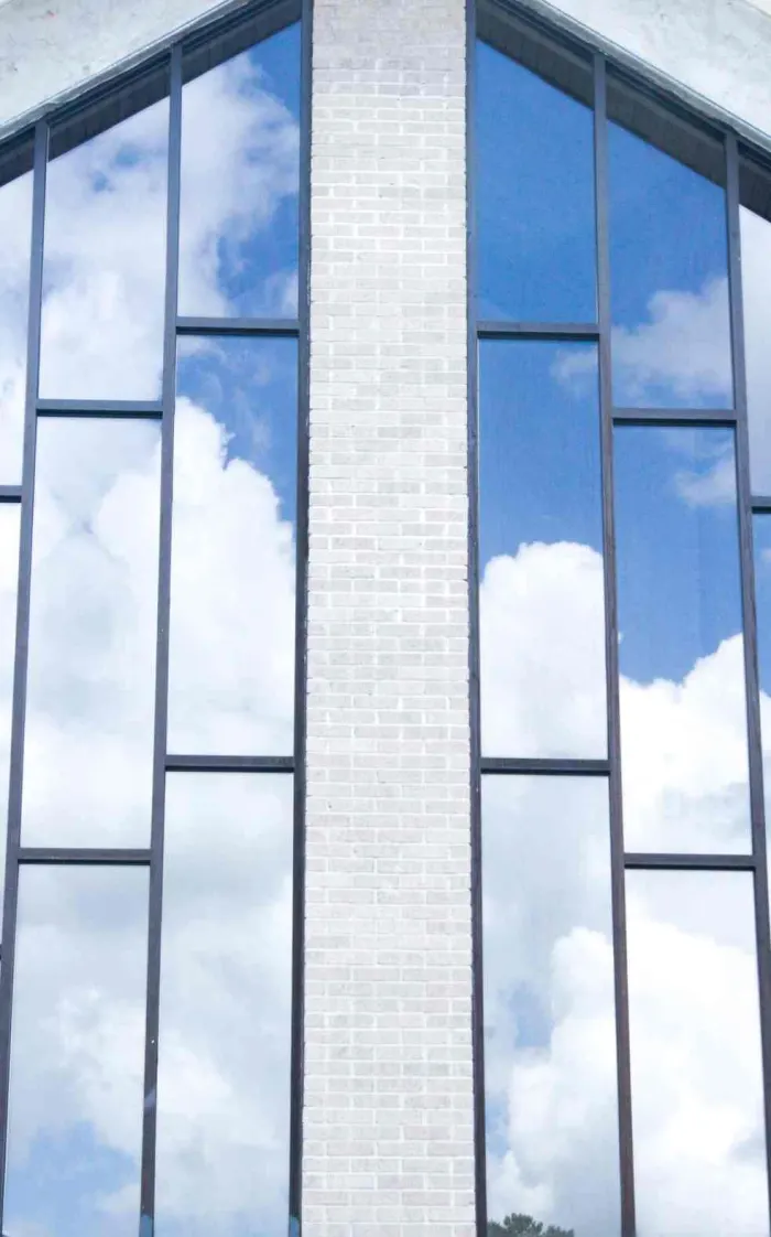 Tall sanctuary windows reflecting blue sky and clouds